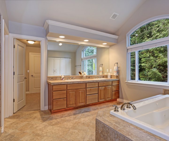 Stunning master bathroom with double vanity cabinet, large arched window, vaulted ceiling and luxury spa tub.